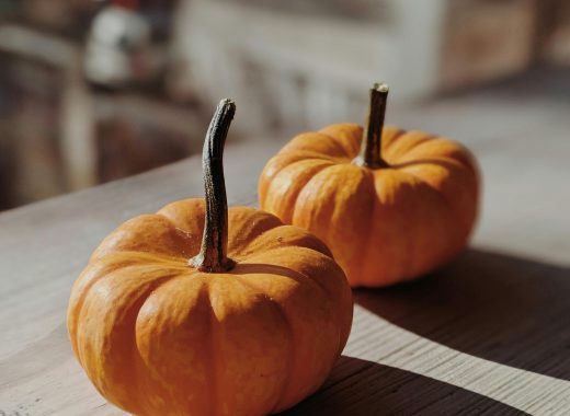 Citrouilles orange de saison posées sur une table en bois, symbole d’automne et d’abondance