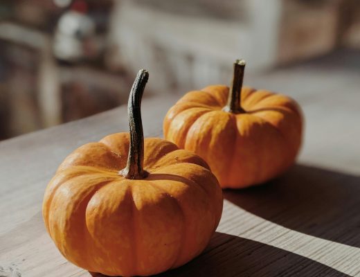 Citrouilles orange de saison posées sur une table en bois, symbole d’automne et d’abondance